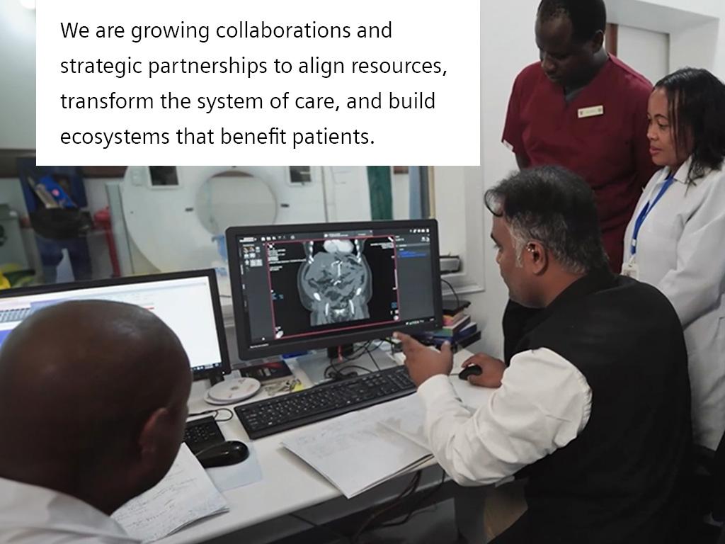 Medical staff sit in front of a screen in the scanning control room.