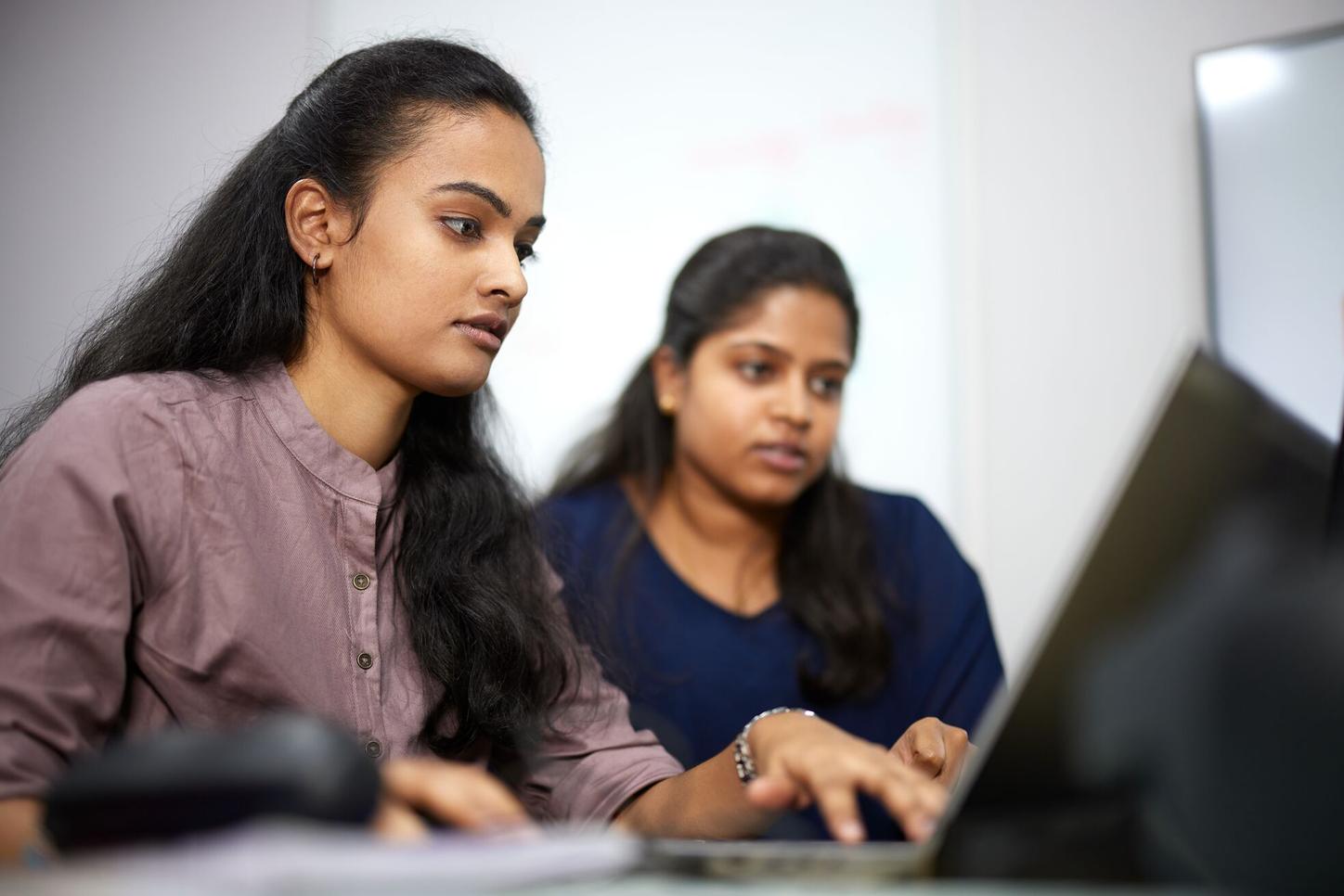 Two female Siemens Healthineers employees from India are looking at a computer while working.