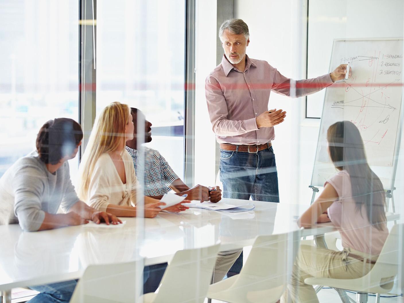 Man at a whiteboard in front of his colleagues meeting