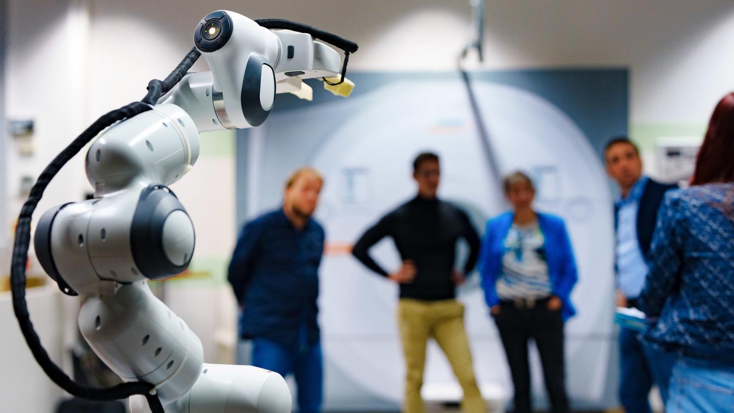 Photo from the innovation lab. In the foreground, we see the gripper of the AURORA assistant robot prototype in focus. In the background, Chiheb Dahmani and three team members are standing, but they are out of focus.