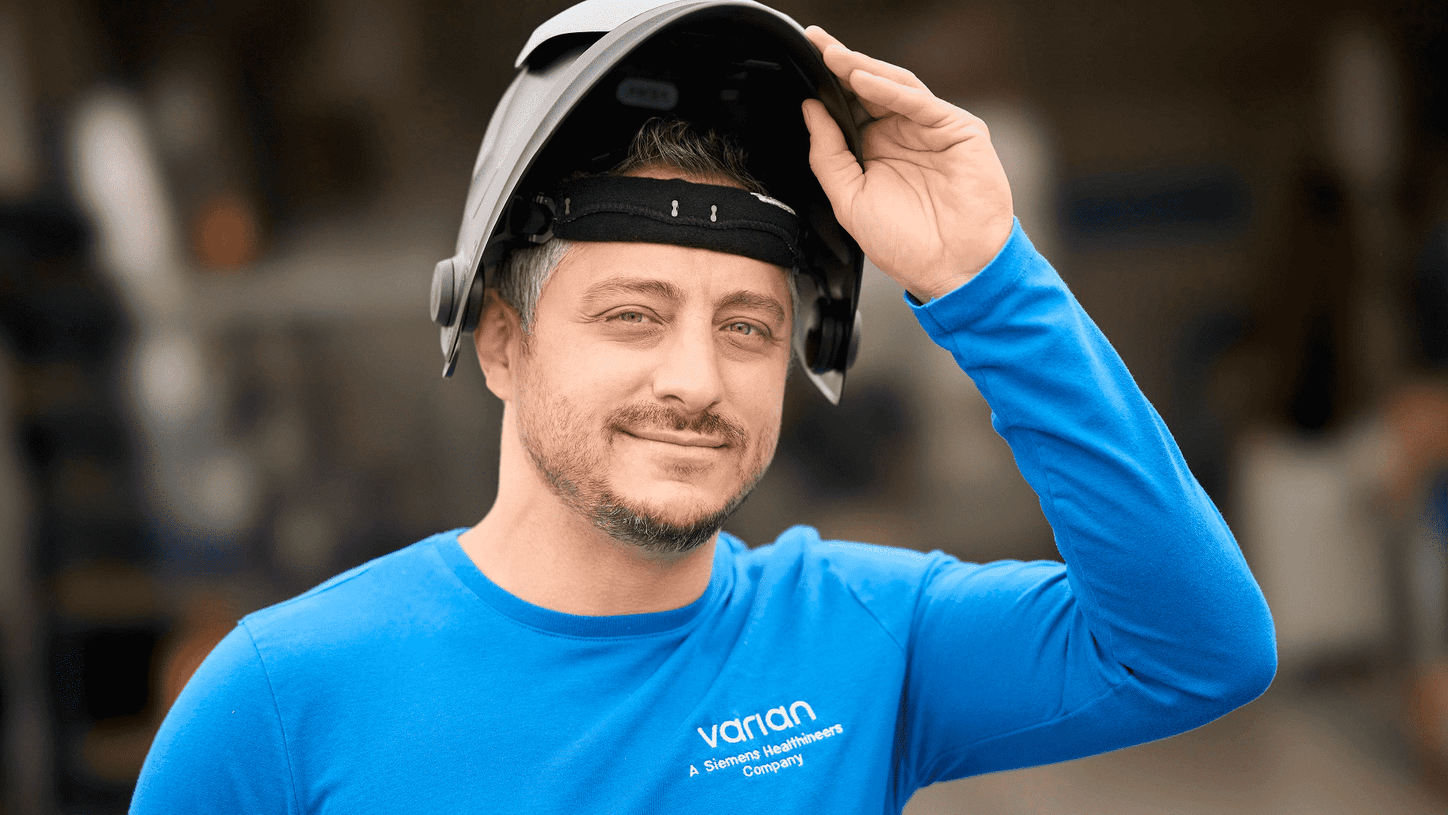Varian employee in production site is taking is helmet off.
